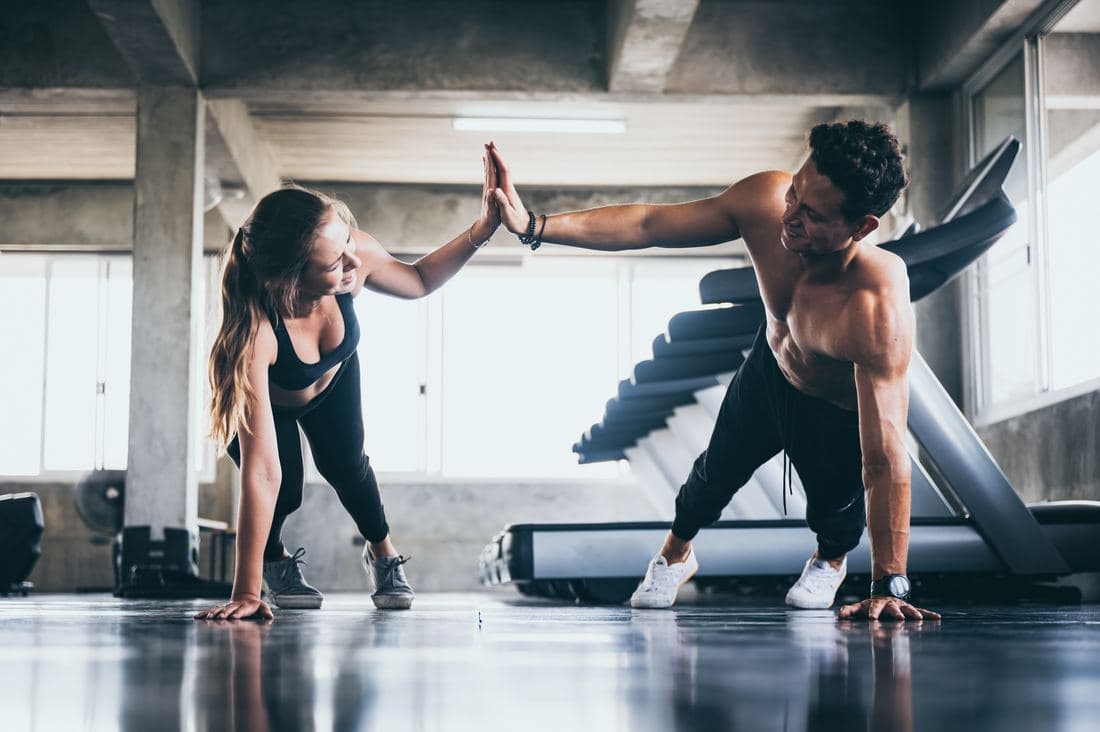 Zwei Sportler klatschen sich im Fitnessstudio ab